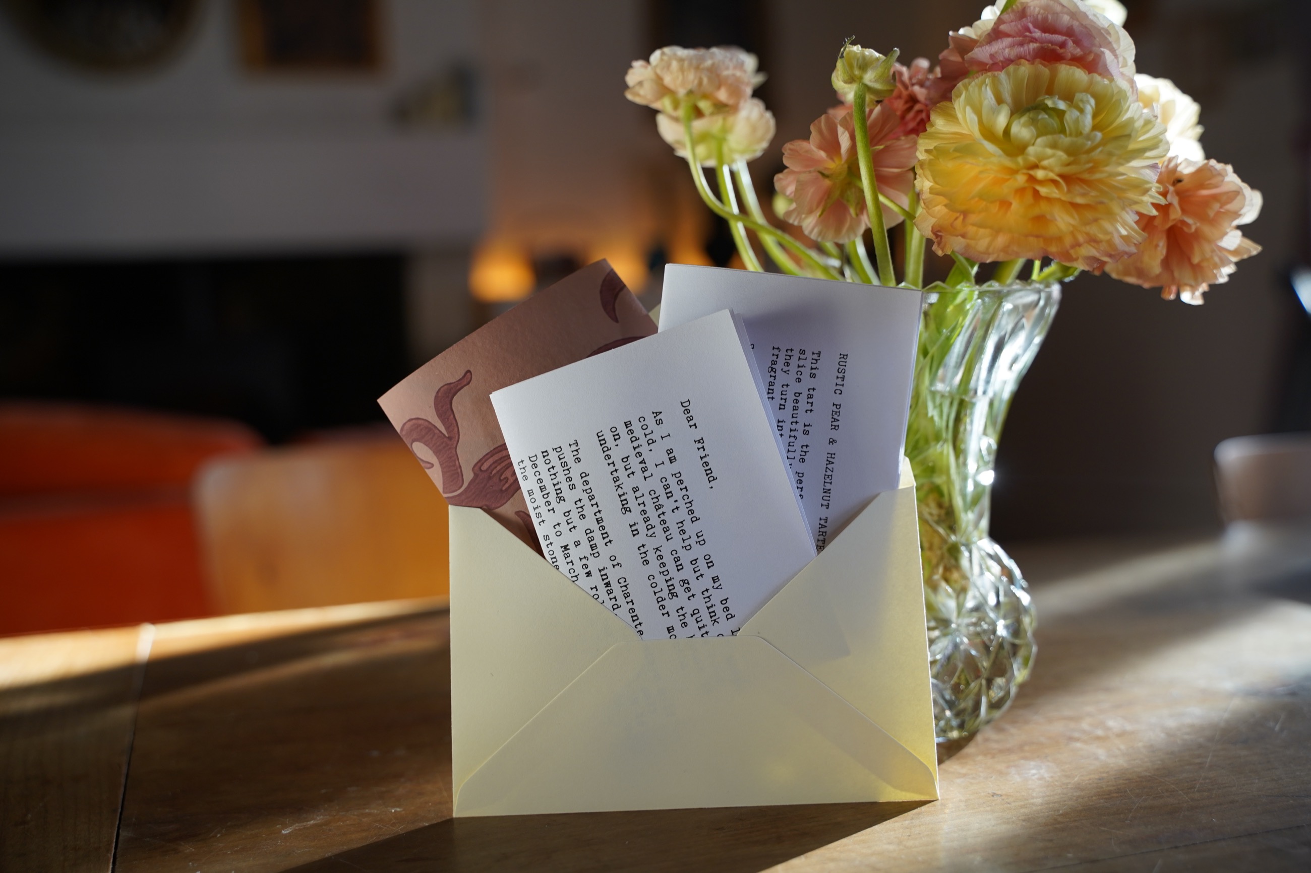 A Château Letter, recipe card and printed keepsake arranged in an envelope beside fresh flowers