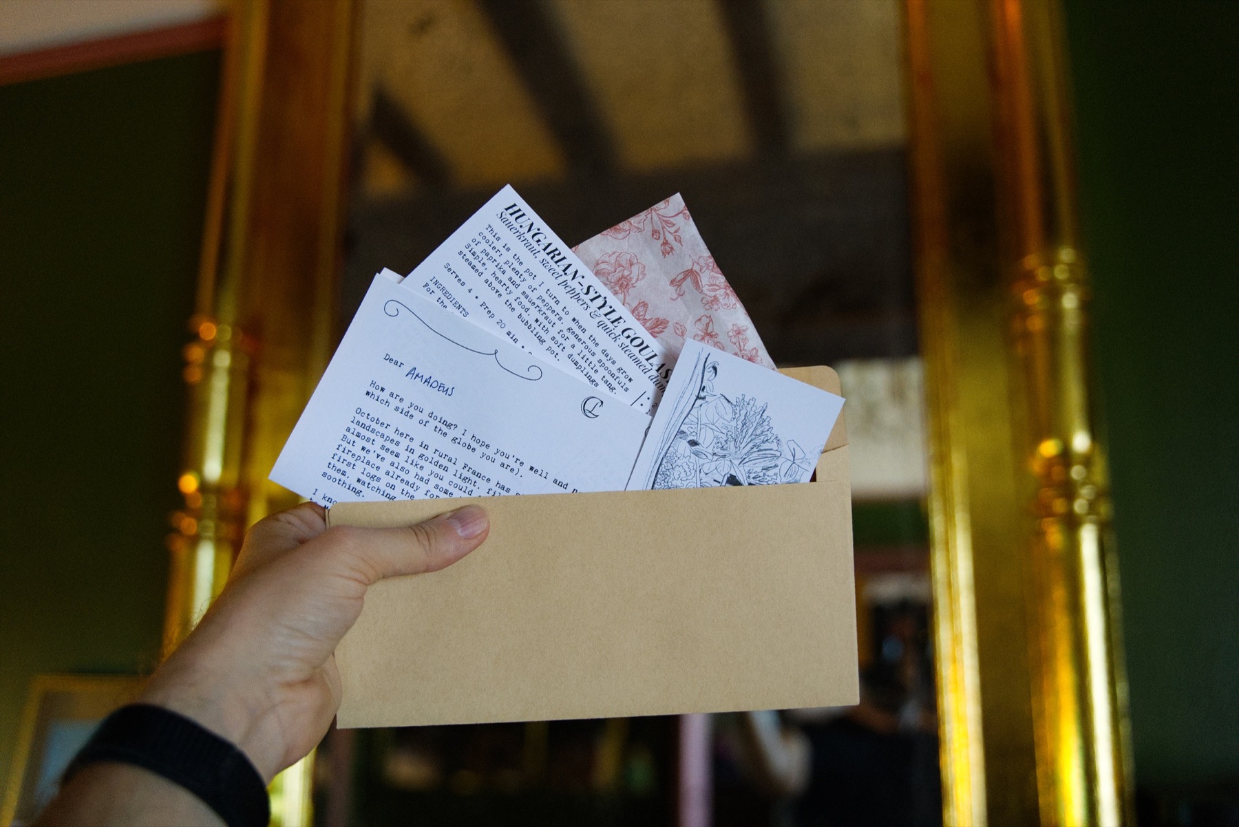 A complete Château Letter held in one hand, showing the letter, recipe, sketch and wrapping